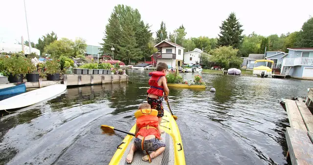 Kids on a paddle board in a lakeside canal